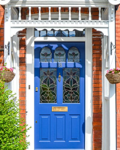 Edwardian botanic front door. Edwardian front door painted rich blue with botanical stained glass. Door is fitted into a london home with a decorative period canopy. Wide front door with secuity locks