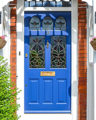 Edwardian botanic front door. Edwardian front door painted rich blue with botanical stained glass. Door is fitted into a london home with a decorative period canopy. Wide front door with secuity locks