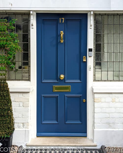 Traditional four panelled Victorian front door. Four panelled door made in solid wood. Door has traditional flat panels with bolection mouldings. Door frame has leaded glass. Door is painted in a rich blue colour in Teknos paint. Door has brass fittings and high secuirty locks. Fitted into a London home