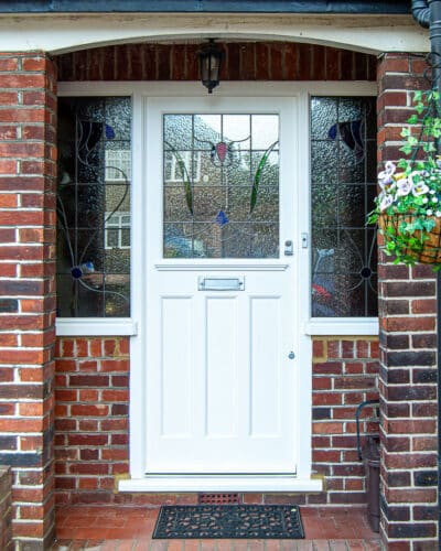 Glazed white 1930's door. Replica of orginal design 1930's front door and stained glass. Door and frame are painted white. Stained glass is coloured and also is laminated and double glazed. Satin chrome door furniture and secuirty locks. Fitted into a london home with red bricks.