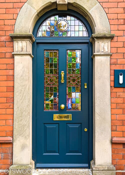 Leadlight Victorian front door. Royal blue front door and new arched top door frame fitted into a stone portico. Door frame has a semi circular glazed transom. Door and frame painted in Teknos paint. insulated door and specially laminated leaded lights with coloured glass. Door is classic victorian style with raised panels. Door has polished brass door furniture and a doctor knocker